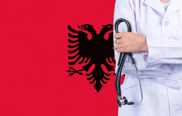 Female doctor with stethoscope in hand on the background of the Albania flag. Concept medicine, pandemic in the country