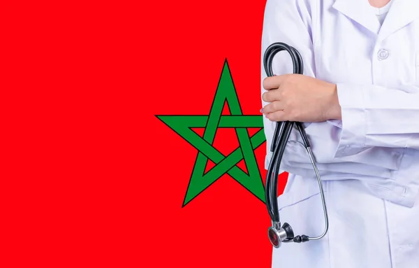 Female doctor with stethoscope in hand on the background of the Morocco flag. Concept medicine, pandemic in the country