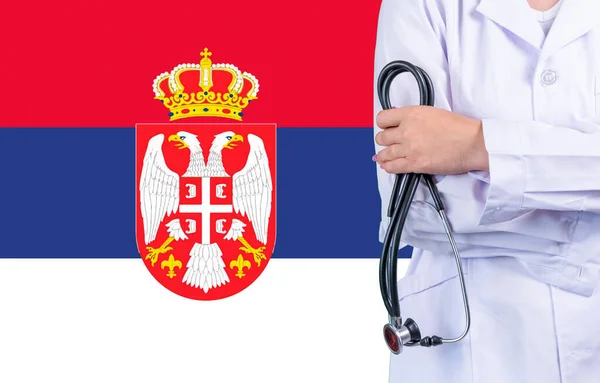 Female doctor with stethoscope in hand on the background of the Serbia flag. Concept medicine, pandemic in the country