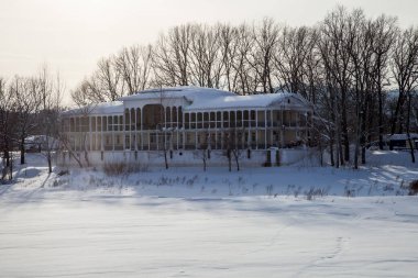 Kışın gölde sütunları olan ev.