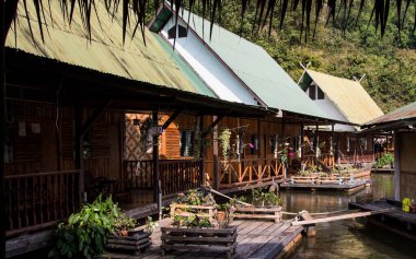 Tayland 'da Kwai Nehri' nin kıyısındaki bir otel. Nehirdeki küçük ahşap evler
