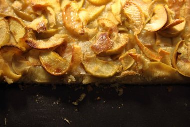 Siyah arka planda sulu elma parçaları olan elmalı turta.