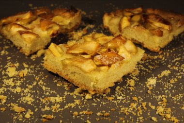 Gri arka planda üç parça elmalı turta ve kırıntılar.