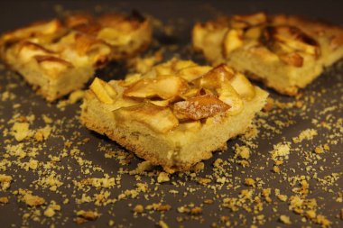 Gri arka planda üç parça elmalı turta ve kırıntılar.