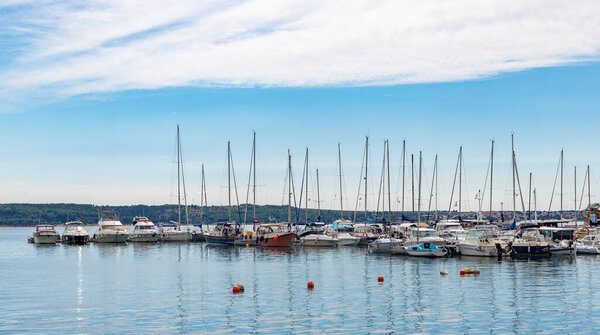 Фотография группы парусников и обычных лодок, пристыкованных к пристани Порторожа.