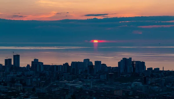 A picture of the sun setting over the Black Sea and the city of Batumi.