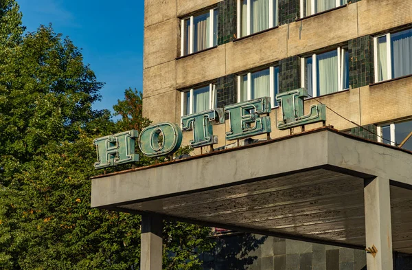 A picture of the hotel sign in front of a hotel.