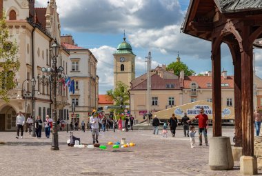 Rzeszow 'un ana meydanında, Saint Adalbert ve Saint Stanislaus kilisesinin kulesiyle büyük sabun köpükleri yaratan bir sokak sanatçısının resmi..