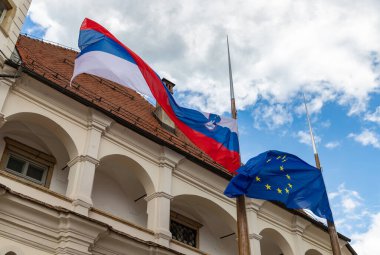 Maribor Kalesi önünde Slovenya ve Avrupa Birliği bayraklarının resmi.