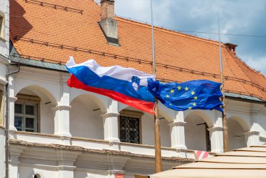 Maribor Kalesi önünde Slovenya ve Avrupa Birliği bayraklarının resmi.