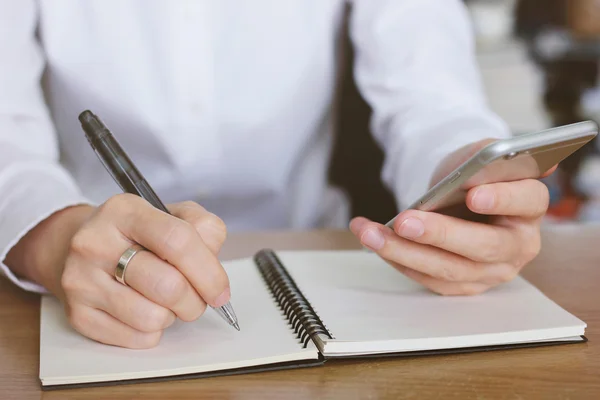 Mujer usando smartphone y escritura — Foto de Stock