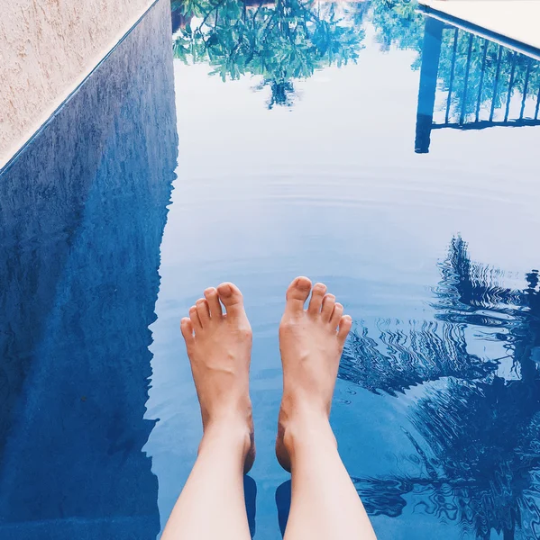 Pernas femininas na água da piscina — Fotografia de Stock