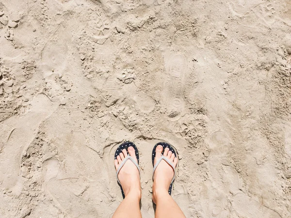 Pés femininos em sandálias na praia — Fotografia de Stock