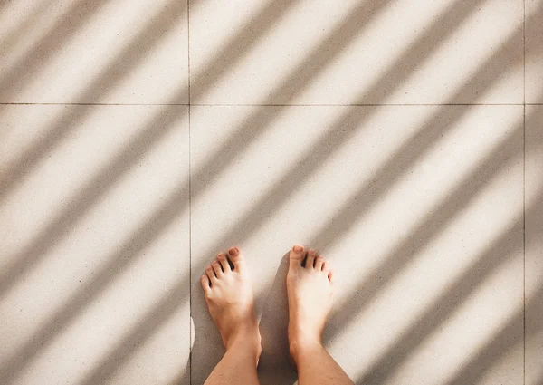 Barefoot person standing on pavement floor Stock Picture