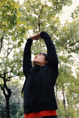 Genç Asyalı sağlıklı bir adam park, egzersiz ve spor antrenmanı konseptinde ısınıp ısınıyor.