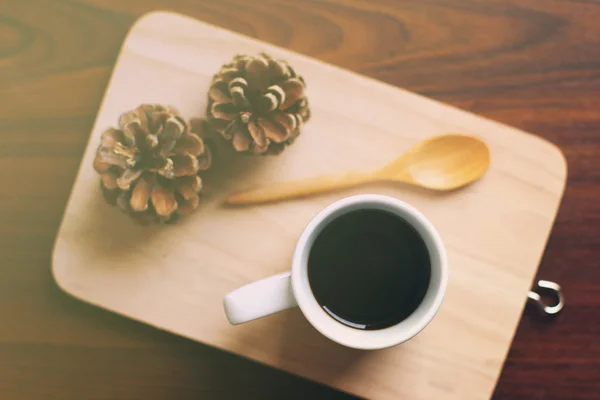 Coffee and spoon on wooden tray with pine cone — Stock Photo, Image
