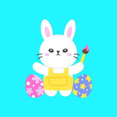 Paskalya Tavşanı, Parlak Mavi Arkaplanda Süslemeli Yumurtaların Yanında Dururken Bir Boya Fırçası Tutuyor ve Elini Kaldırıyor