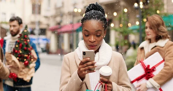 Radostná Afroameričanka Vyzdobeném Městě Šálkem Kávy Textovkou Smartphonu Přijímající Vánoční — Stock fotografie
