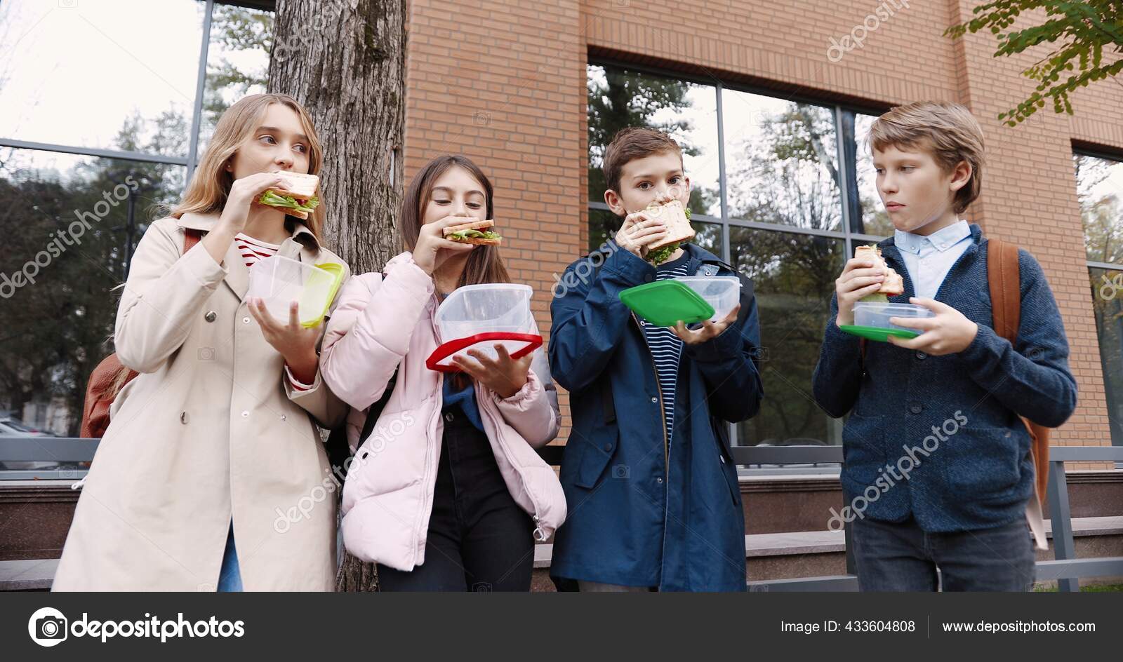 一个快乐的白人小学生站在户外 拿着食物盒和三明治的画像 男生和女生 放学时在学校附近带着背包吃午饭 图库照片 C Vaksmanv101 一个快乐的白人小学生站在户外 拿着食物盒和三明治的画像 男生和女生 放学时在学校附近带着背包吃午饭 图库照片 C Vaksmanv101