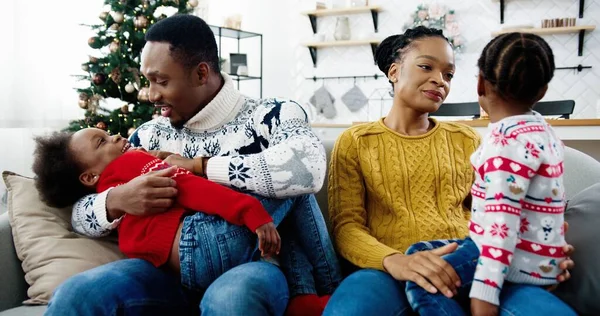 Close-up van vrolijke familie in goed humeur zitten in versierd modern huis met kerst. Gelukkig vader spelen met kind terwijl moeder praten met een ander kind. Familie vakantie concept. Nieuwjaarsstemming — Stockfoto