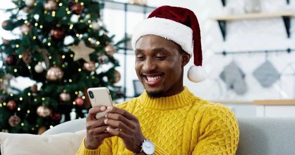 Afro-americano alegre homem surpreso na véspera de Natal receber grandes notícias no celular sobre loteria vitória leilão vitória sentindo-se feliz. Sorte inacreditável, milagre de Ano Novo, emoções sinceras, venda de Natal — Fotografia de Stock