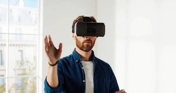 Close up de belo jovem caucasiano vestindo óculos VR, rolando com as mãos no ar usando tecnologias de inovações modernas escolhendo design de casa. Conceito de reparação e renovação. Realidade virtual — Fotografia de Stock