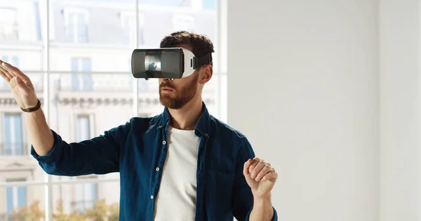 Close up de belo jovem caucasiano vestindo óculos VR, rolando com as mãos no ar usando tecnologias de inovações modernas escolhendo design de casa. Conceito de reparação e renovação. Realidade virtual — Fotografia de Stock