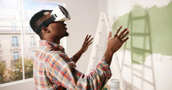 Close up de jovem afro-americano impressionado homem animado fica no quarto vestindo óculos VR e olhando para o novo apartamento renovado redesenhado usando inovações modernas. Tecnologia de realidade virtual — Fotografia de Stock