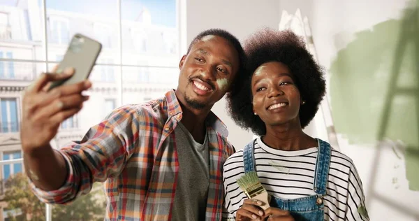 Zavřít. POV šťastný Afroameričan mladá žena a manžel s malovanými tvářemi mluvit na video chat on-line na tablet zařízení stojící v novém bytě při renovaci domova. Oprava domu — Stock fotografie