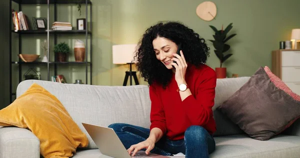 Кавказка красивая счастливая молодая женщина печатает в Интернете на ноутбуке, используя социальные медиа сидя на диване дома, студент учится на компьютере в гостиной с помощью цифрового гаджета — стоковое фото