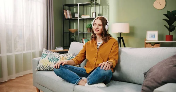 Genç, güzel, beyaz bir kız, evde tek başına, kulaklıkla oturuyor ve müzik dinlemekten hoşlanıyor..