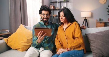 Hindu mutlu, genç, sakallı koca internette internette sörf yapıyor güzel eşiyle sosyal ağ uygulaması, olumlu ruh hali, aile ilişkileri konsepti hakkında konuşuyor.