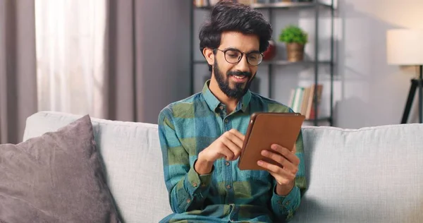 Närbild av Hindu unga stilig glad manlig köpare i glasögon shopping på nätet köpa på internet surfa på surfplatta enhet tittar på kameran och ler, e-handel service koncept — Stockfoto