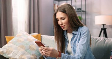 Oturma odasındaki kanepede dinlenen bir kadın akıllı telefonuyla kablosuz internet üzerinde geziniyor. Milenyum kızı evdeki kanepede dinleniyor ve modern cep telefonuna mesaj atıyor. Teknoloji konsepti