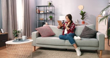 Harcayacak kadar nakitim var. Kanepede dinlenirken internetten alışveriş yapan bir kadın. Kredi kartı bilgilerini yazarken tablet kullanan bir kız. Online ödeme yapmak için kartını kullanan bir kadının görüntüsü.