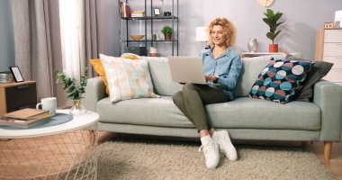 Kanepede oturup dizüstü bilgisayar kullanan ve kart detaylarına giren gülümseyen bir kız. İnternet üzerinden alışveriş yapan mutlu bir kadın. Kolay bankacılık sistemi hizmeti kavramı