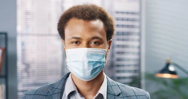 Закріпіть портрет щасливого афроамериканського робітника в медичній масці, який дивиться на камеру в кімнаті і посміхається. Бізнесмен в карантині. Бізнес, робота, ковидна пандемія — стокове фото