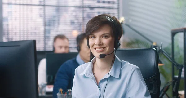 Nahaufnahme Porträt einer glücklichen jungen kaukasischen schönen Callcenter-Betreiberin, die am Schreibtisch im Kabinett sitzt, mit Headset in die Kamera schaut und lächelt. Fröhliche Mitarbeiterin bei der Arbeit, Arbeiterkonzept — Stockfoto