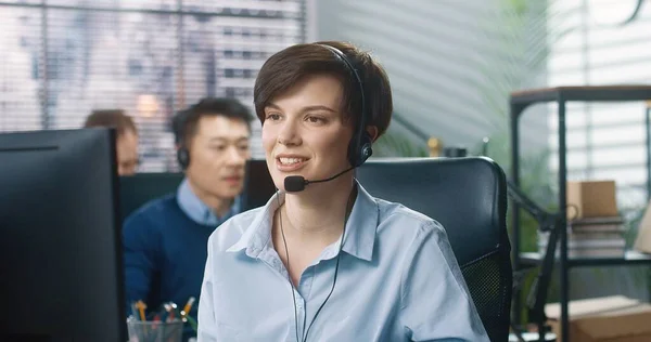 Nahaufnahme Porträt einer glücklichen jungen kaukasischen schönen Callcenter-Betreiberin, die am Schreibtisch im Kabinett sitzt, mit Headset in die Kamera schaut und lächelt. Fröhliche Mitarbeiterin bei der Arbeit, Arbeiterkonzept — Stockfoto