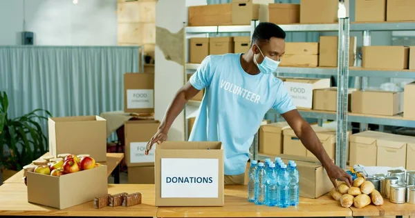 Africano americano jovem bonito feliz homem armazém trabalhador voluntário trabalhando no transporte entrega caridade estoque organização embalagem doações caixa Doando e voluntariado, conceito de centro de caridade — Fotografia de Stock