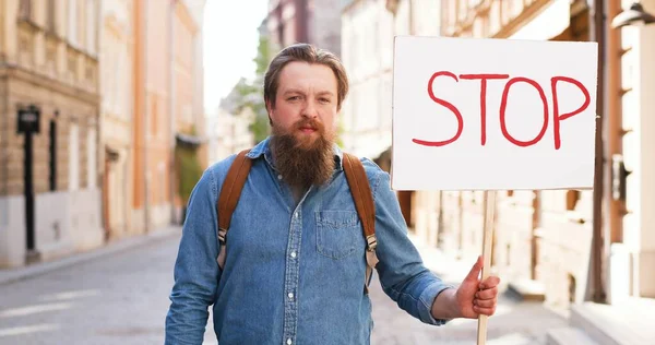 Portrait d'un homme activiste caucasien portant la barbe affiche Arrêtez-vous à une manifestation politique ou environnementale solitaire en ville. Une seule manifestation dehors. Concept d'activisme. Homme protestant seul. — Photo