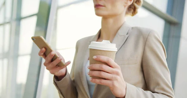 Ofis merkezinde takım elbiseli bir iş kadını yürürken akıllı telefon ve kahve taşıyan kadınların ellerini kapat.. — Stok fotoğraf