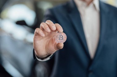 Erkek, yeni araba almak için Bitcoin 'i dijital parayla tutuyor. Bitcoin ile araba değişimi. Şifreleme