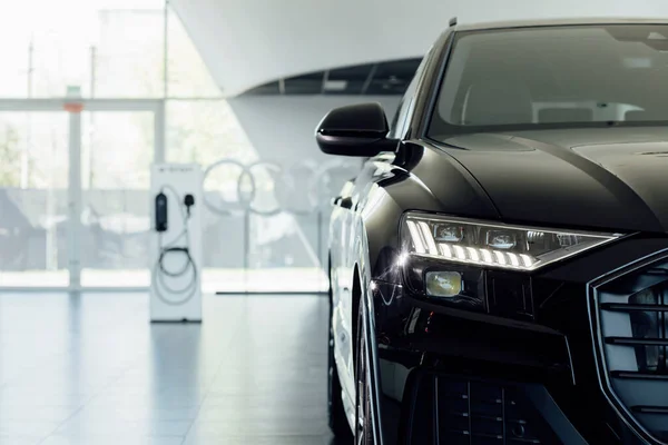 Coches nuevos en la sala de exposición del distribuidor. Coche eléctrico, estación de carga de vehículos eléctricos. Lámpara del faro del coche nuevo, espacio de copia. — Foto de Stock