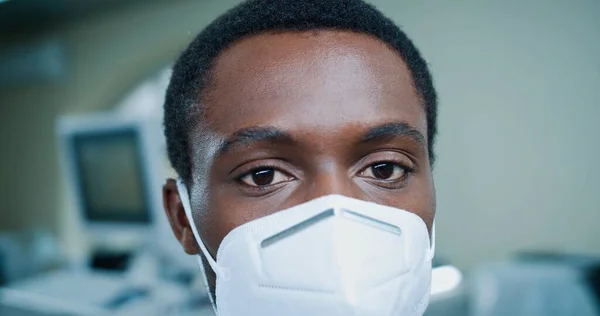 아프리카 계 미국인젊은 의사가 마스크를 쓴 채 카메라를 보고 있는 사진을 클로즈업했습니다. 병원에서 일하는 사람들, 의료 개념, 코로나 바이러스 대유행, 의료 전문가, 의료 계, 의료 계 — 스톡 사진