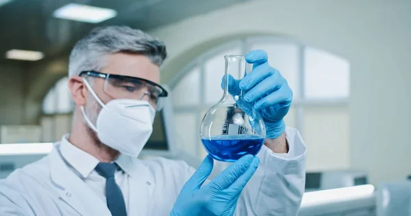 카프카스의 약사가마스크와 고글을 플라스크에서 연구를 액체를 있습니다 실험실 서비스를 제공하고 — 스톡 사진
