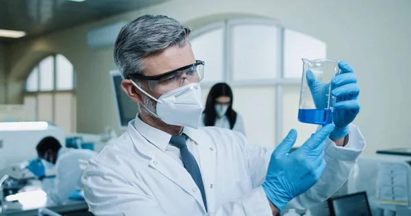 Caucasian Male Pharmacist Mask Goggles Working Lab Examining Blue Liquid — Stockfoto