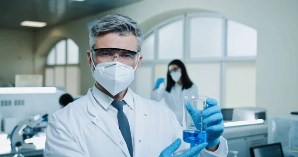Caucasian Male Pharmacist Mask Goggles Working Lab Examining Blue Liquid — Zdjęcie stockowe