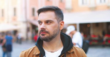 Yakışıklı bir gencin portresi. Yakışıklı bir gülümseme ve sağlıklı dişler. Sokakta yürüdükten sonra..