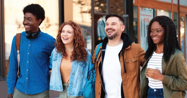 Portrait of friendly company of people spending great time together while walking at the city with each other at the summer